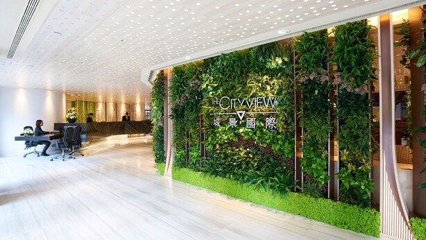 A modern lobby with a green wall and a reception desk. - The Cityview - Chinese YMCA of Hong Kong (Kowloon)
