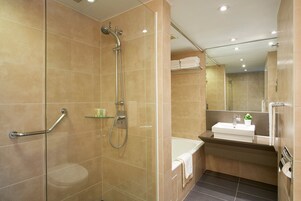 Un baño moderno con ducha de vidrio, lavamanos blanco y espejo.