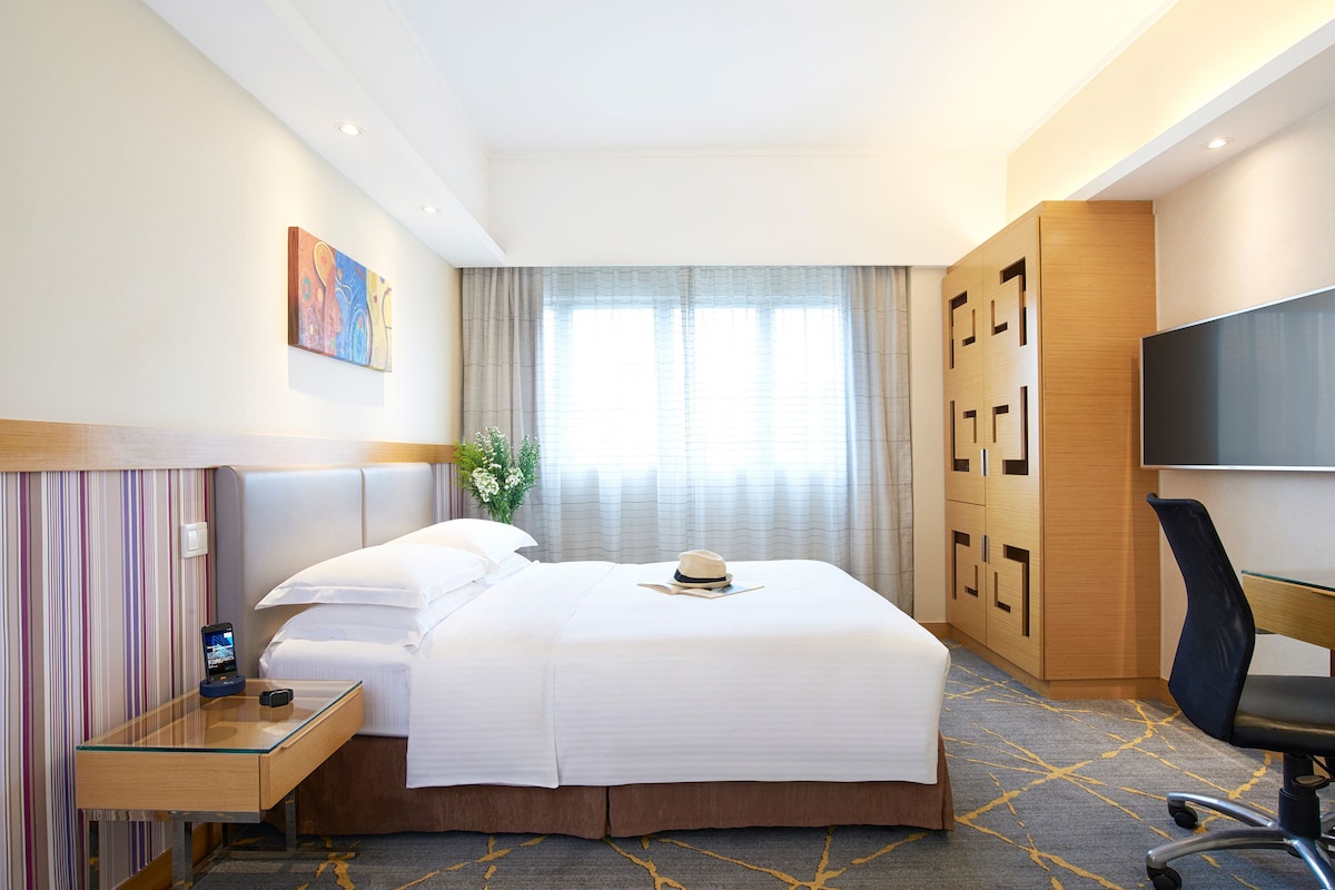 Una habitación de hotel con una cama, un escritorio, un televisor y un armario.