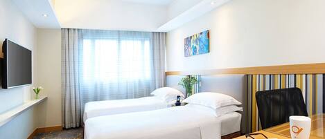 A hotel room with two beds, a desk with a chair, a television, and a window with curtains.
