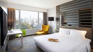 A hotel room with a large bed, a desk with a laptop, a chair, and a view of the city. - The Cityview - Chinese YMCA of Hong Kong (Kowloon)