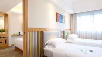 A hotel room with two beds, a painting on the wall, and a window with curtains.