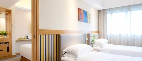 Una habitación de hotel con dos camas, un cuadro en la pared y una ventana con cortinas.