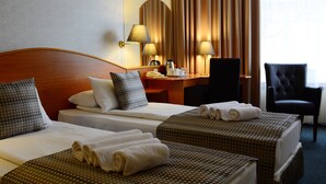 A hotel room with two beds, a desk, a chair, and a lamp. - Hotel Orion (Budapest)