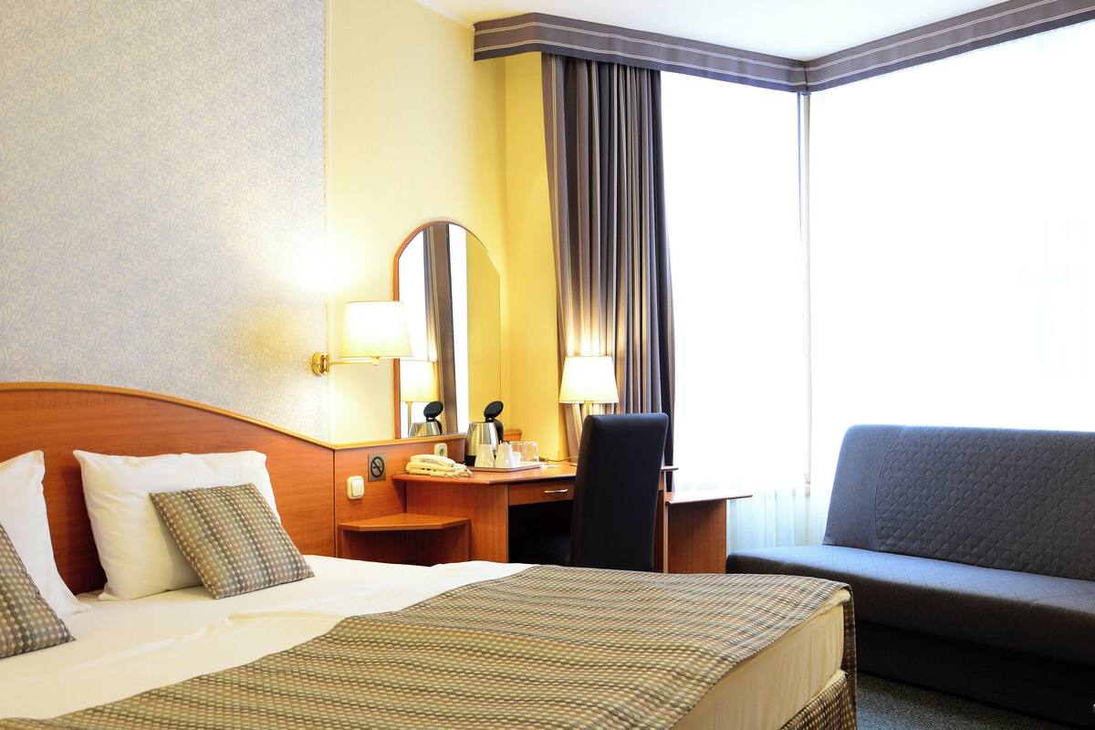 Una habitación de hotel con una cama grande, un escritorio con teléfono, una silla y un sofá.