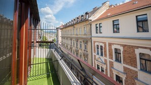 A narrow balcony with a green artificial turf floor, bordered by a metal railing. - Hotel Orion (Budapest)