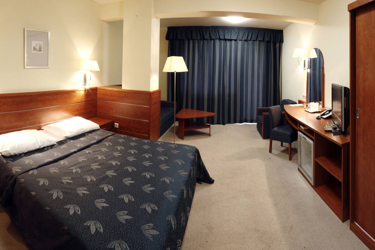 Une chambre d’hôtel équipée d’un lit, d’un bureau, d’une chaise et d’un téléviseur.