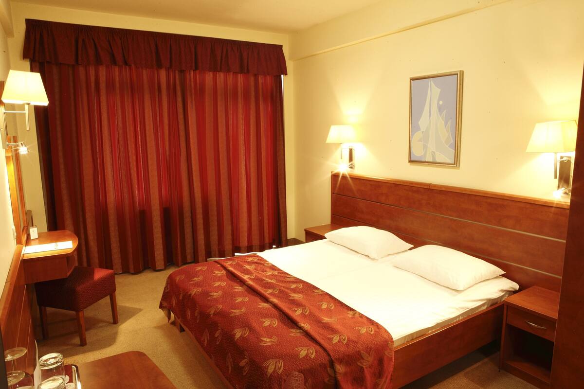 Une chambre d’hôtel avec un grand lit, deux tables de chevet, un bureau et une chaise.