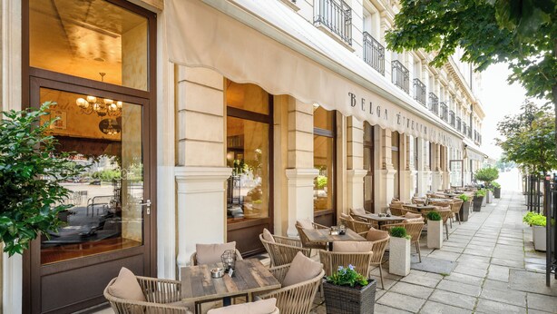 An outdoor café with wicker furniture and potted plants. - Danubius Hotel Rába (Gyor)