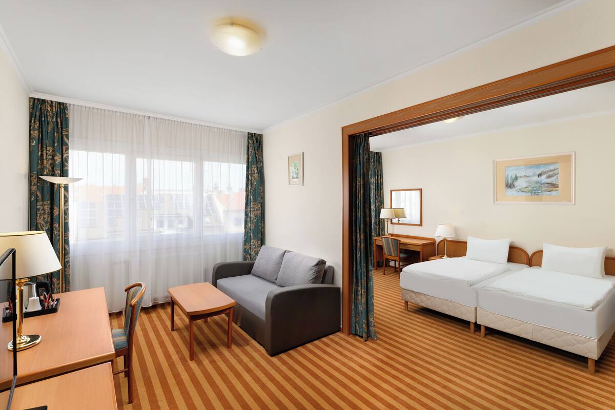 Una habitación de hotel con sofá, cama, escritorio y silla.