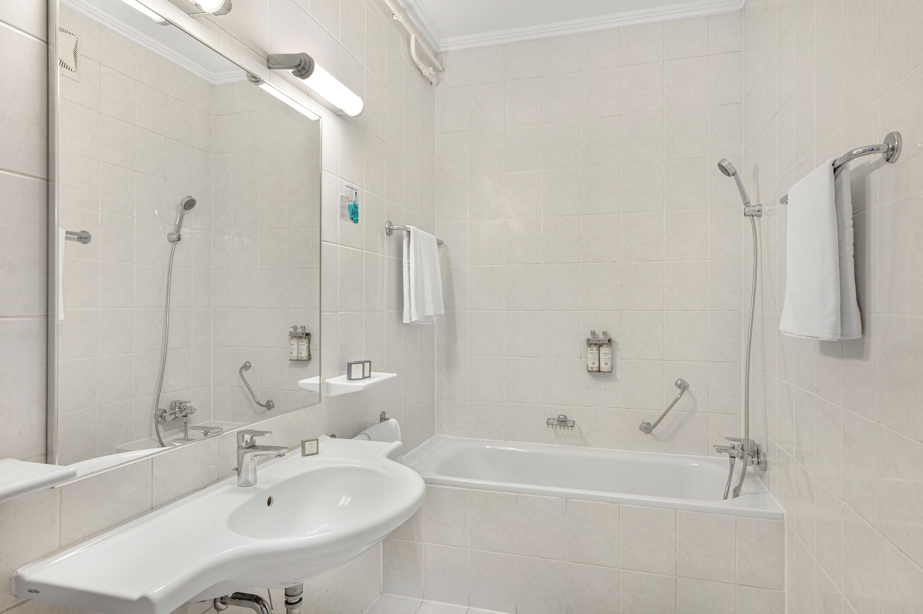 Un baño moderno con un espejo grande, un lavabo, una bañera y una ducha.