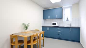 Una cocina compacta con armarios azules, un microondas blanco y una pequeña ventana con una planta.