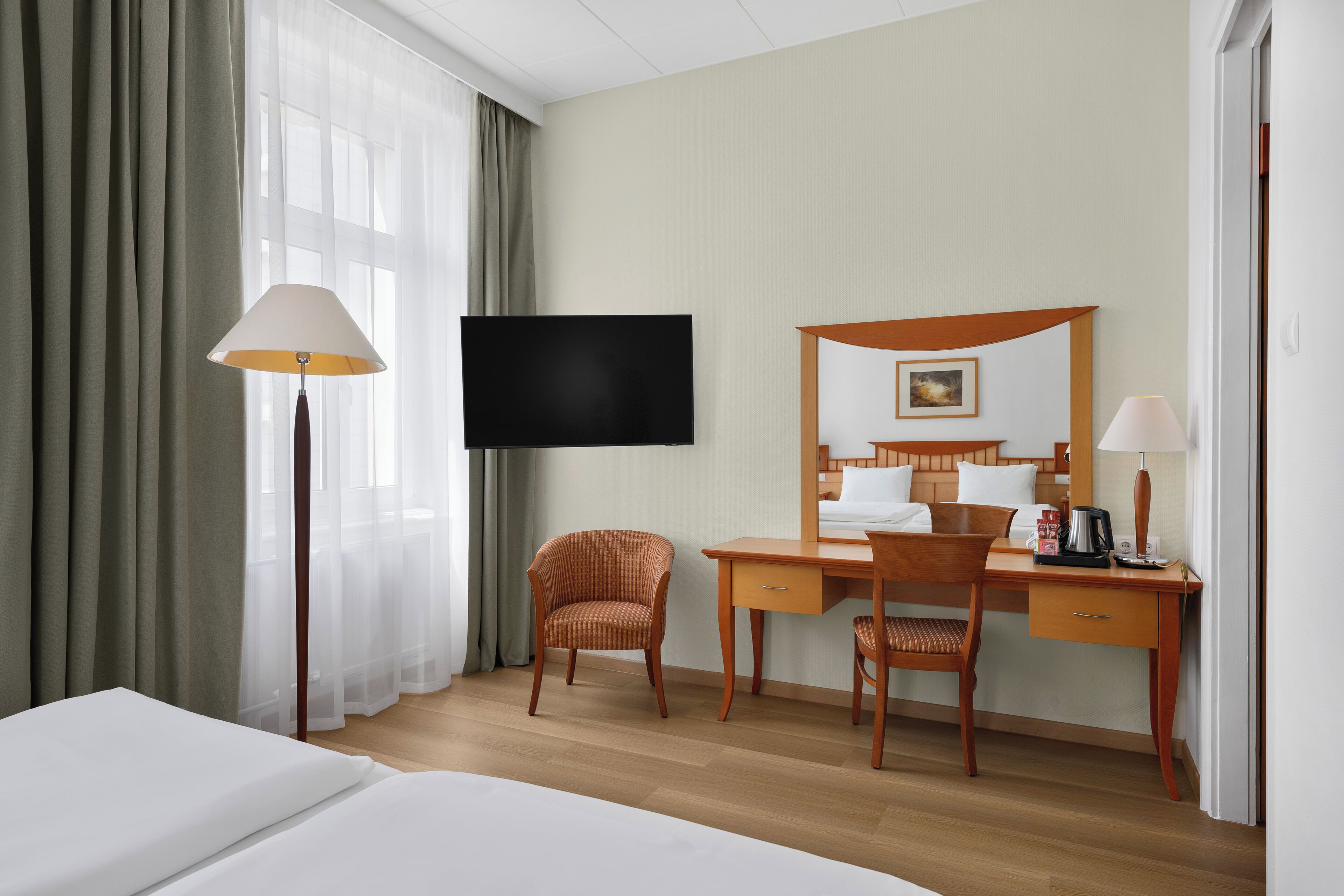 Une chambre d’hôtel comprenant un lit, un bureau avec une chaise, une télévision et une lampe.