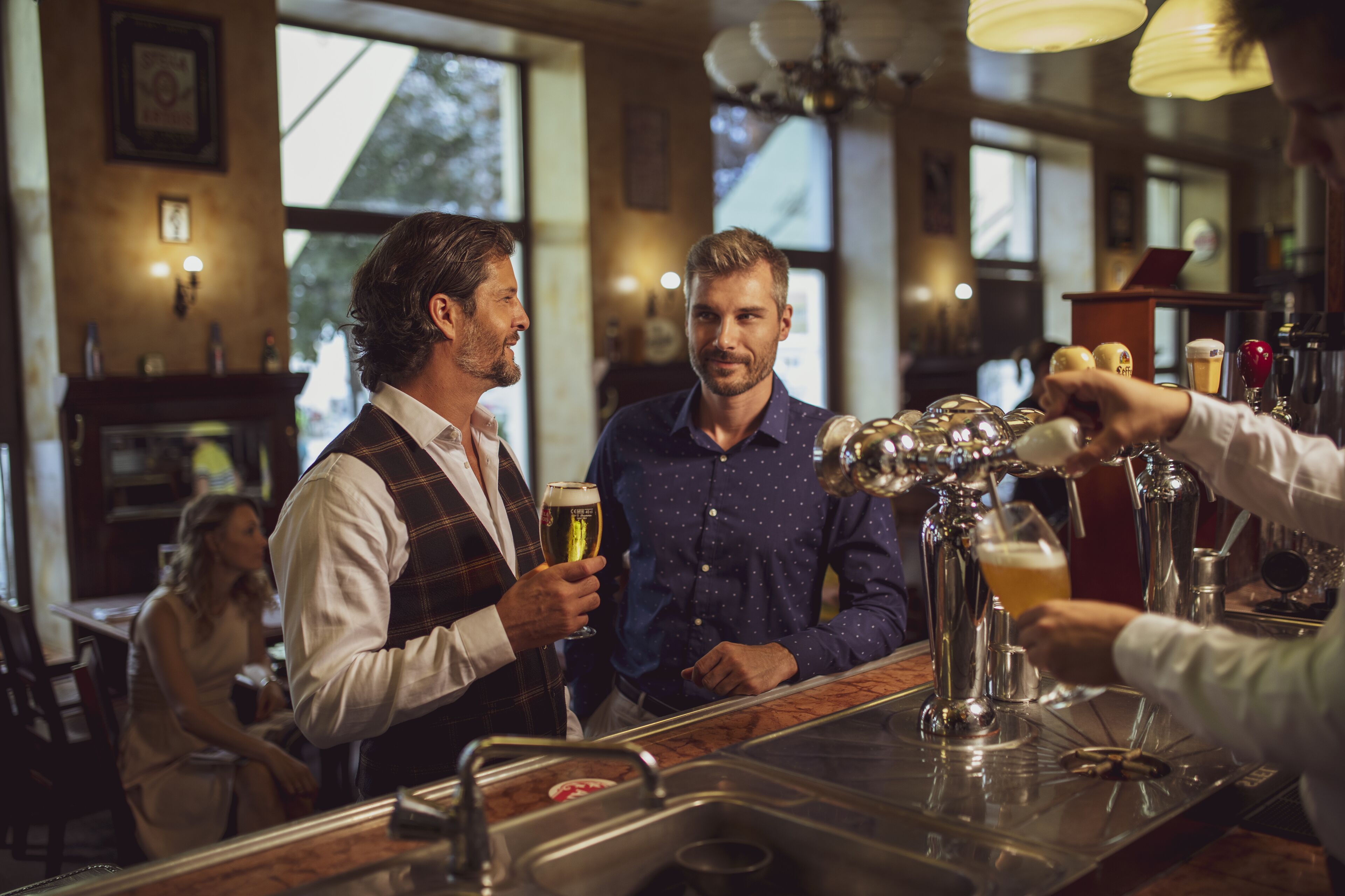 A bar area with a bartender serving drinks to customers.