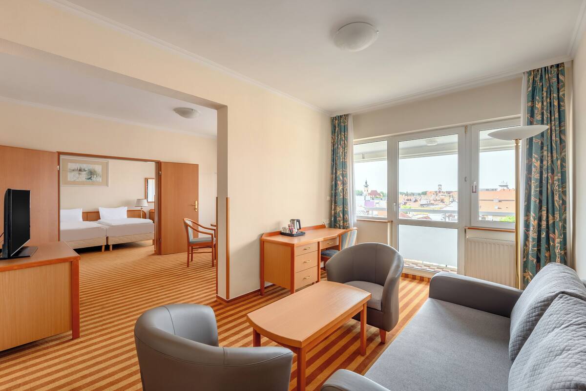Una habitación de hotel con una cama, un escritorio, una silla, un sofá y un amplio ventanal con vistas.