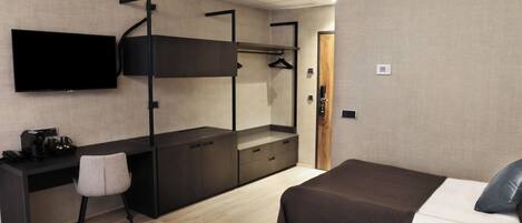 Une chambre d’hôtel moderne équipée d’un lit superposé, d’un bureau avec une chaise, d’un téléviseur à écran plat et d’une armoire.
