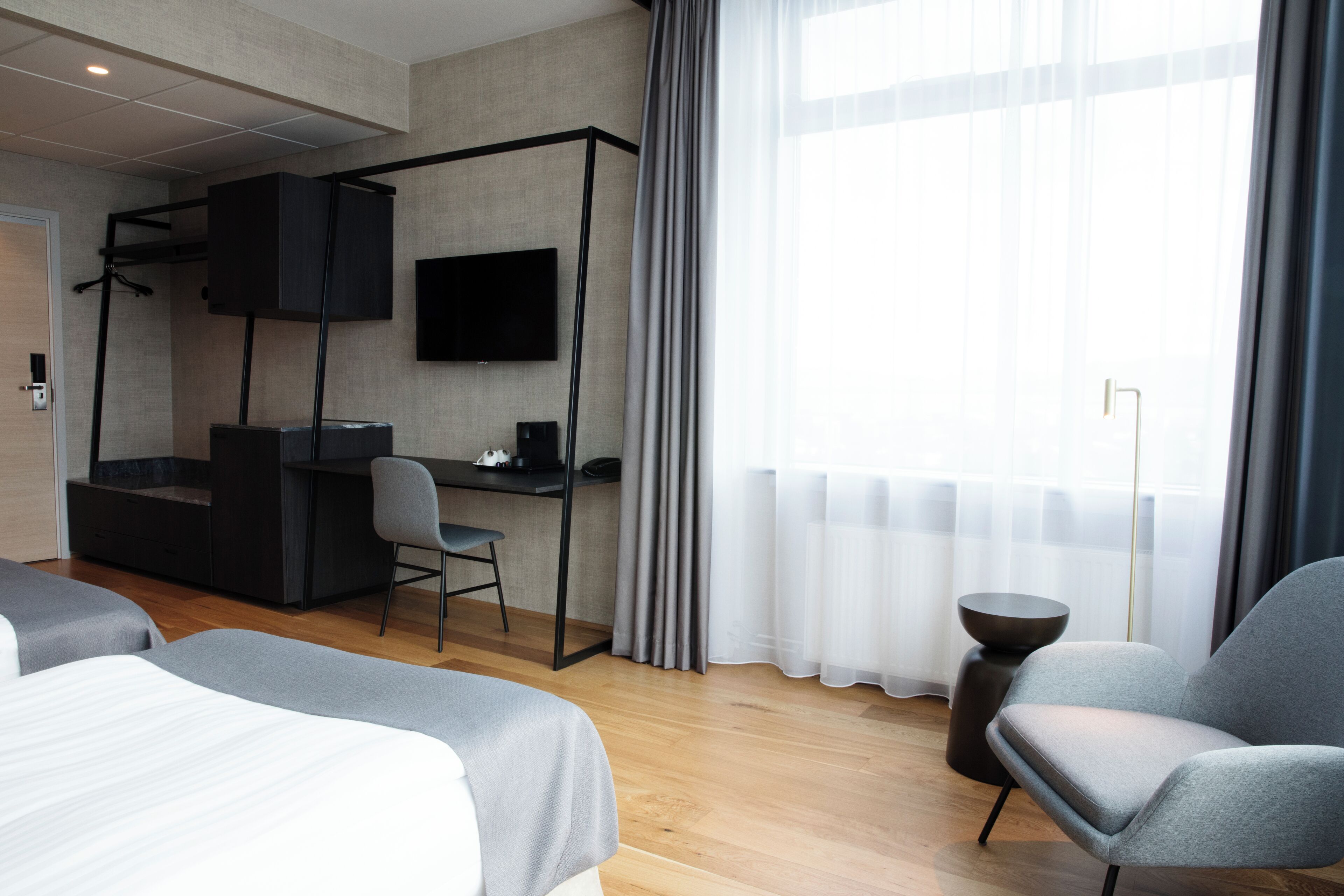 Una habitación de hotel moderna con cama, escritorio, silla y televisión.