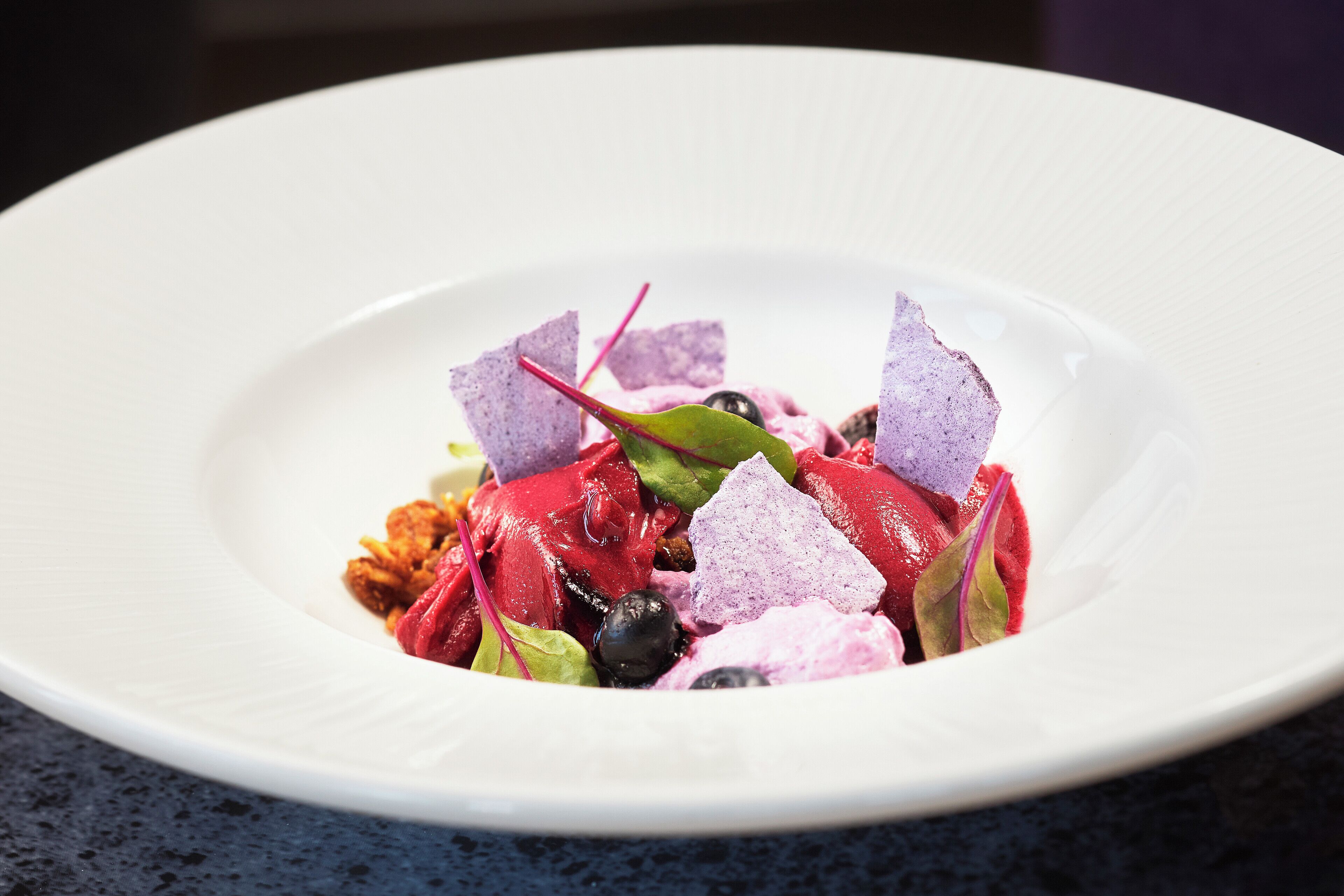 Um prato branco com uma salada colorida sobre uma superfície escura.