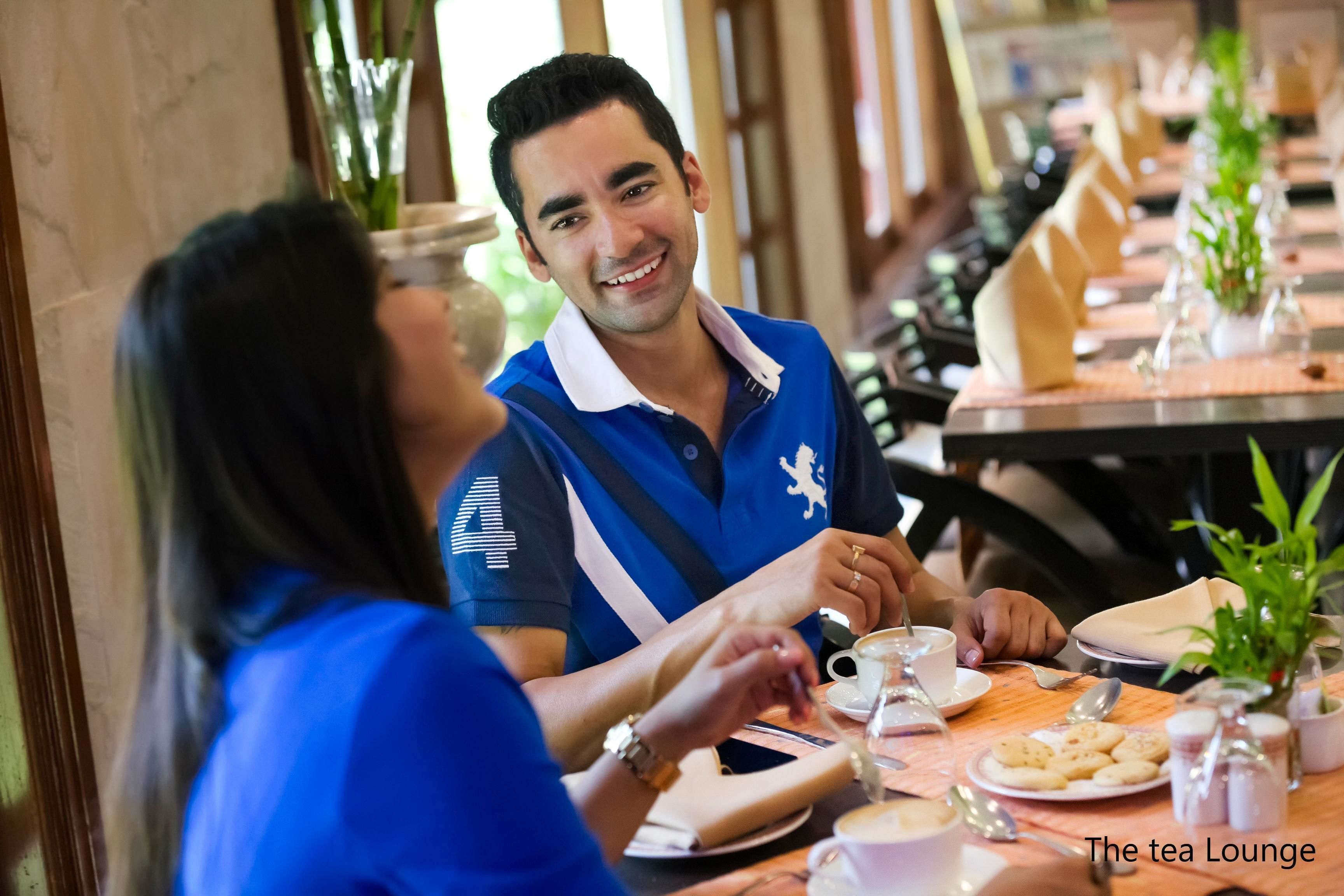 A restaurant setting with a long table, multiple chairs, and a variety of dishes and drinks.