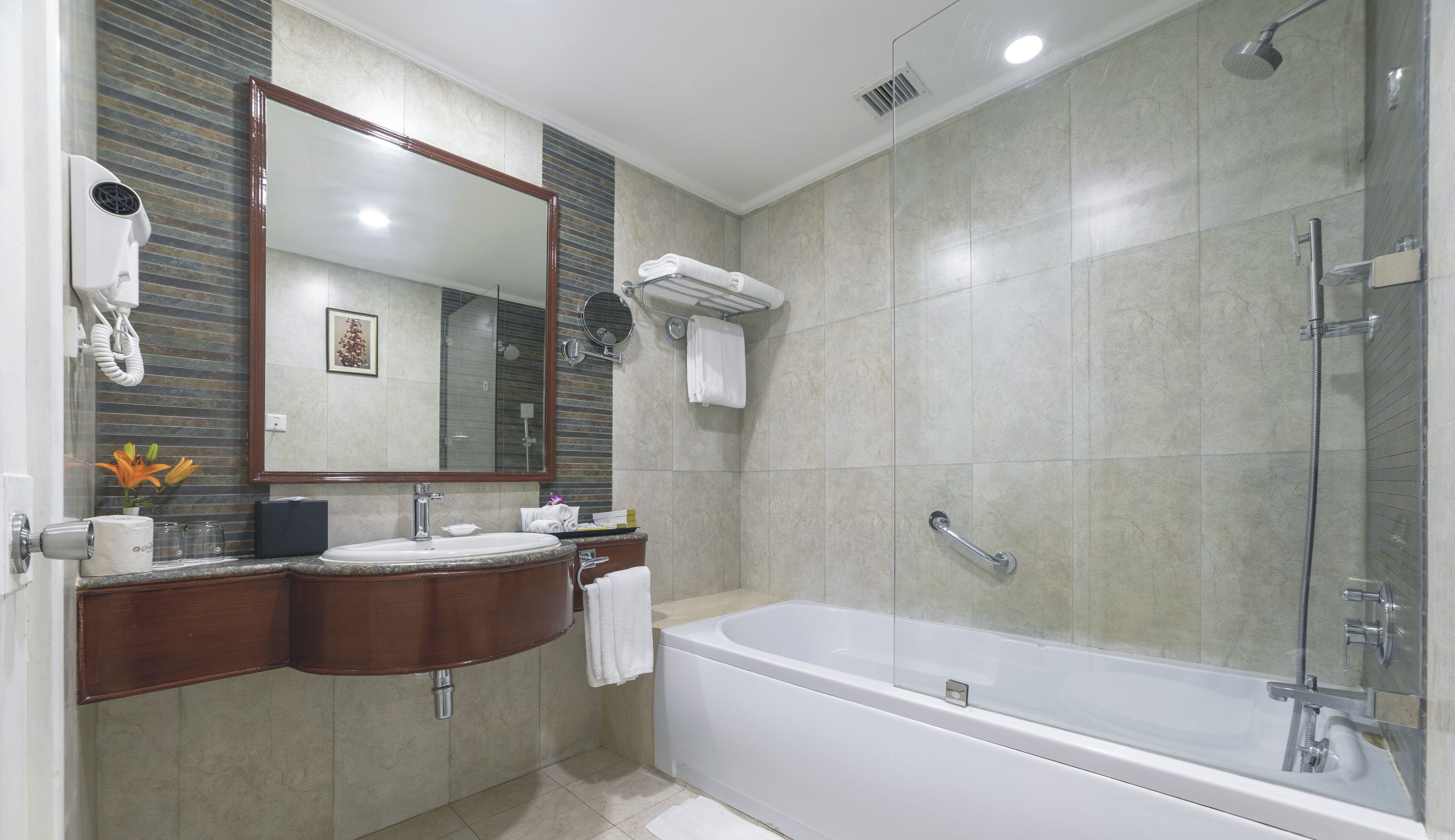 Une salle de bain moderne avec un grand miroir, un lavabo, un meuble-lavabo, une baignoire et une douche.
