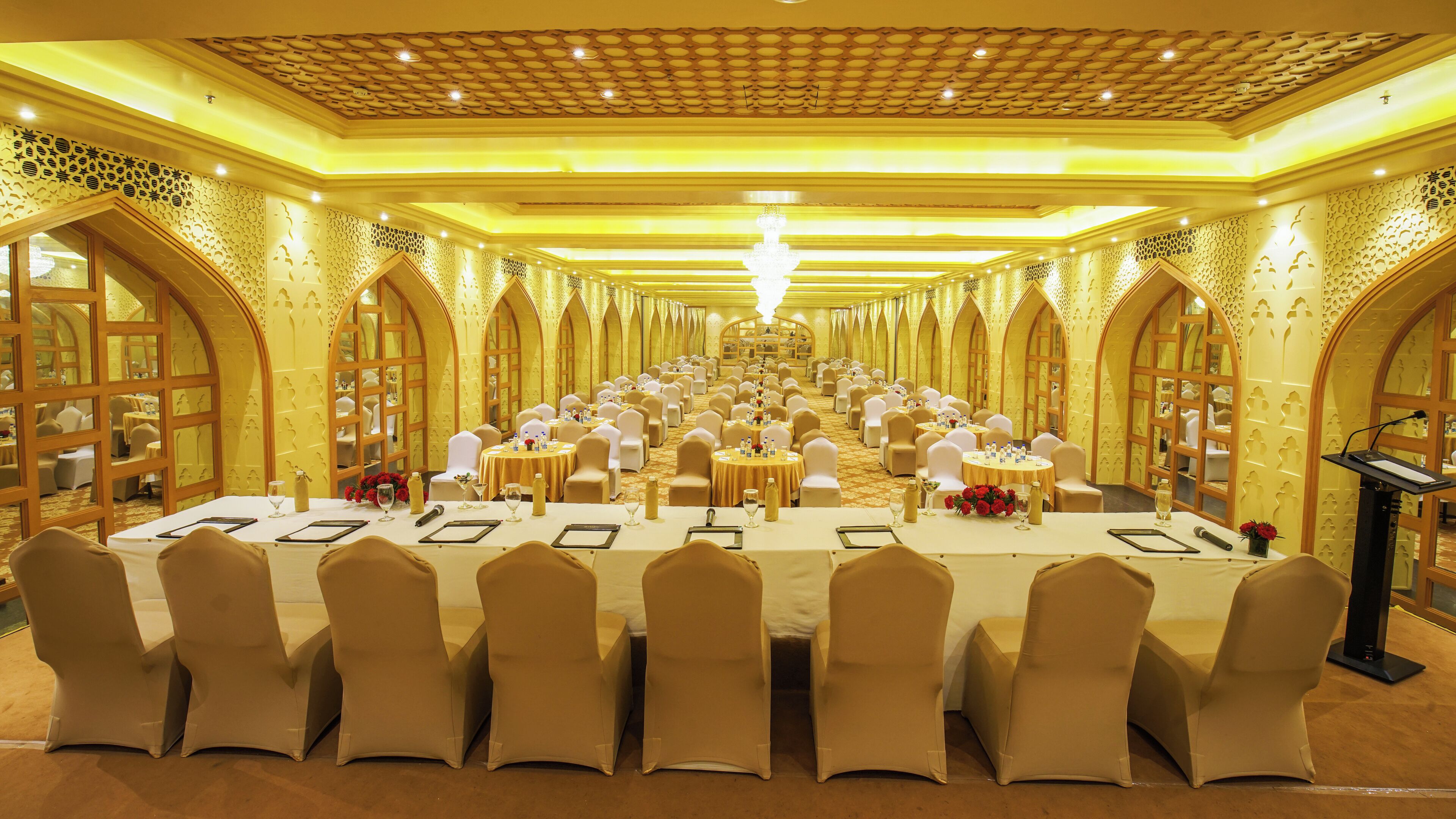 A banquet hall with long tables, chairs, and a central stage.