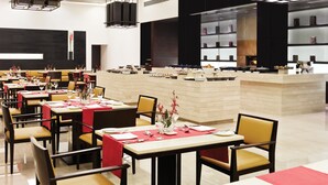 A modern restaurant with multiple dining tables, black chairs, and a central bar area. - Trident, Agra (Agra)