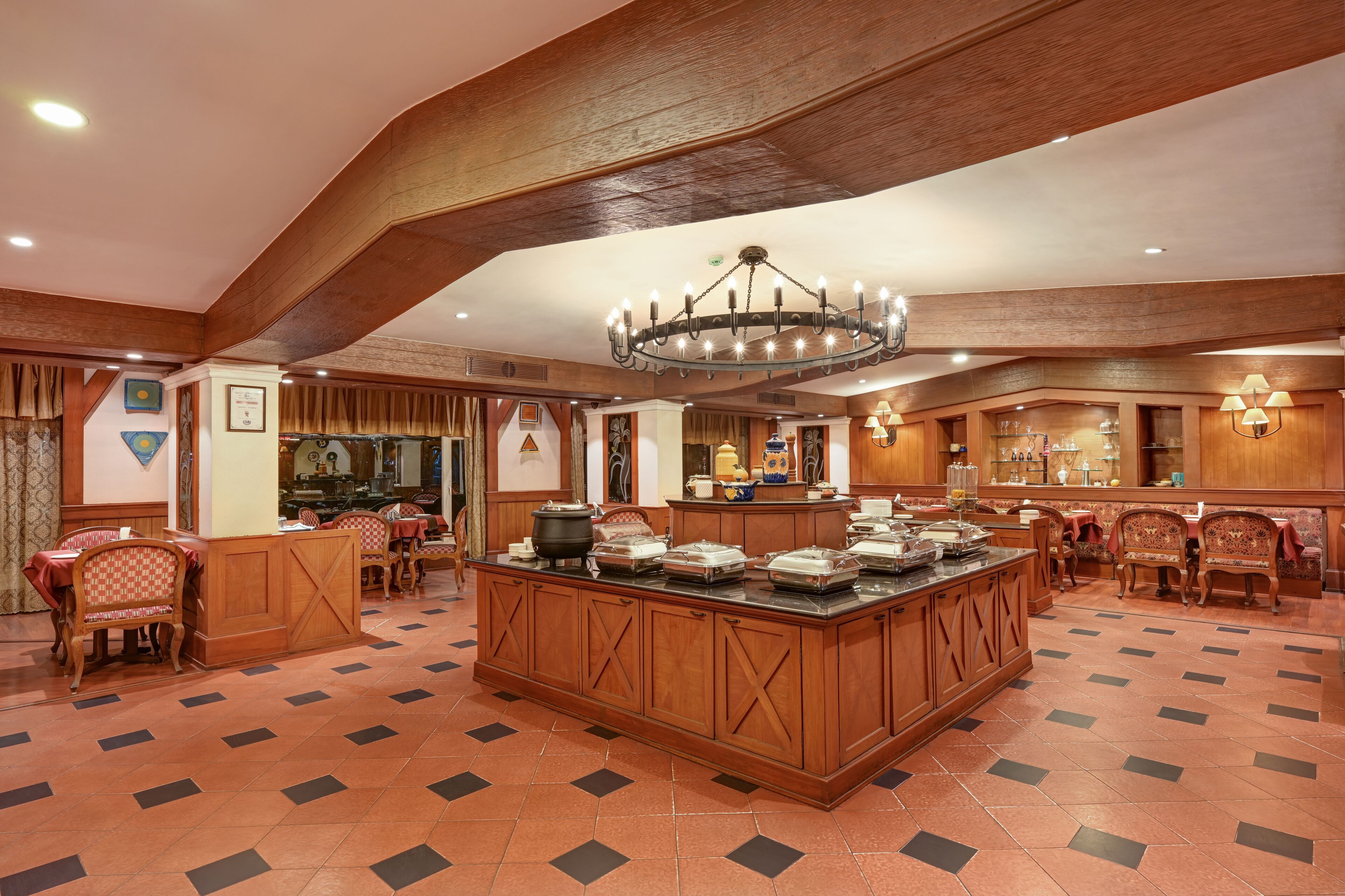A spacious hotel lobby with a central island, wooden paneling, and a chandelier.