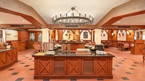 A spacious hotel lobby with a central island, wooden paneling, and a chandelier. - Cama Hotel (Ahmedabad)
