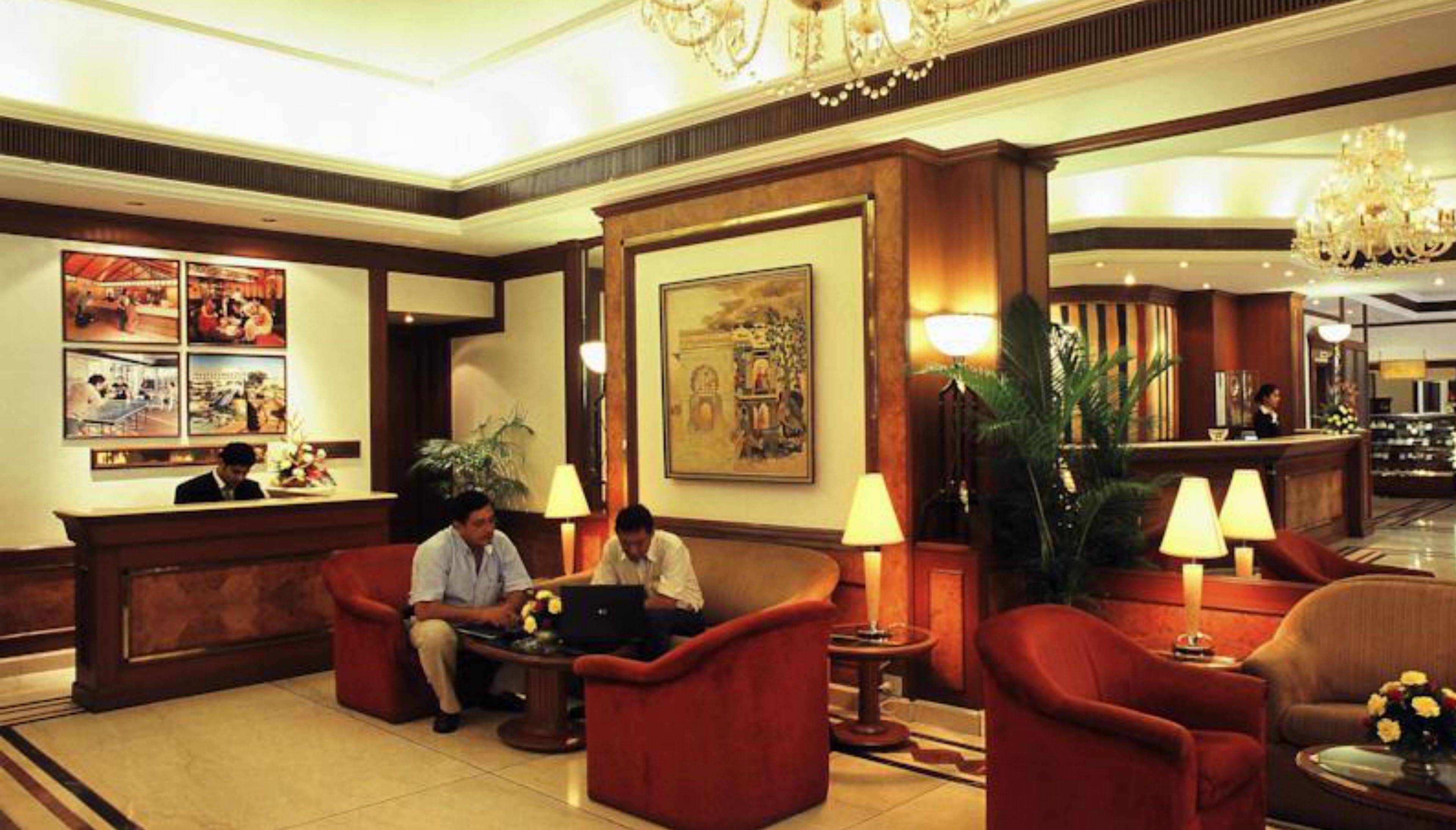 A lobby with red armchairs, a reception desk, and a chandelier.