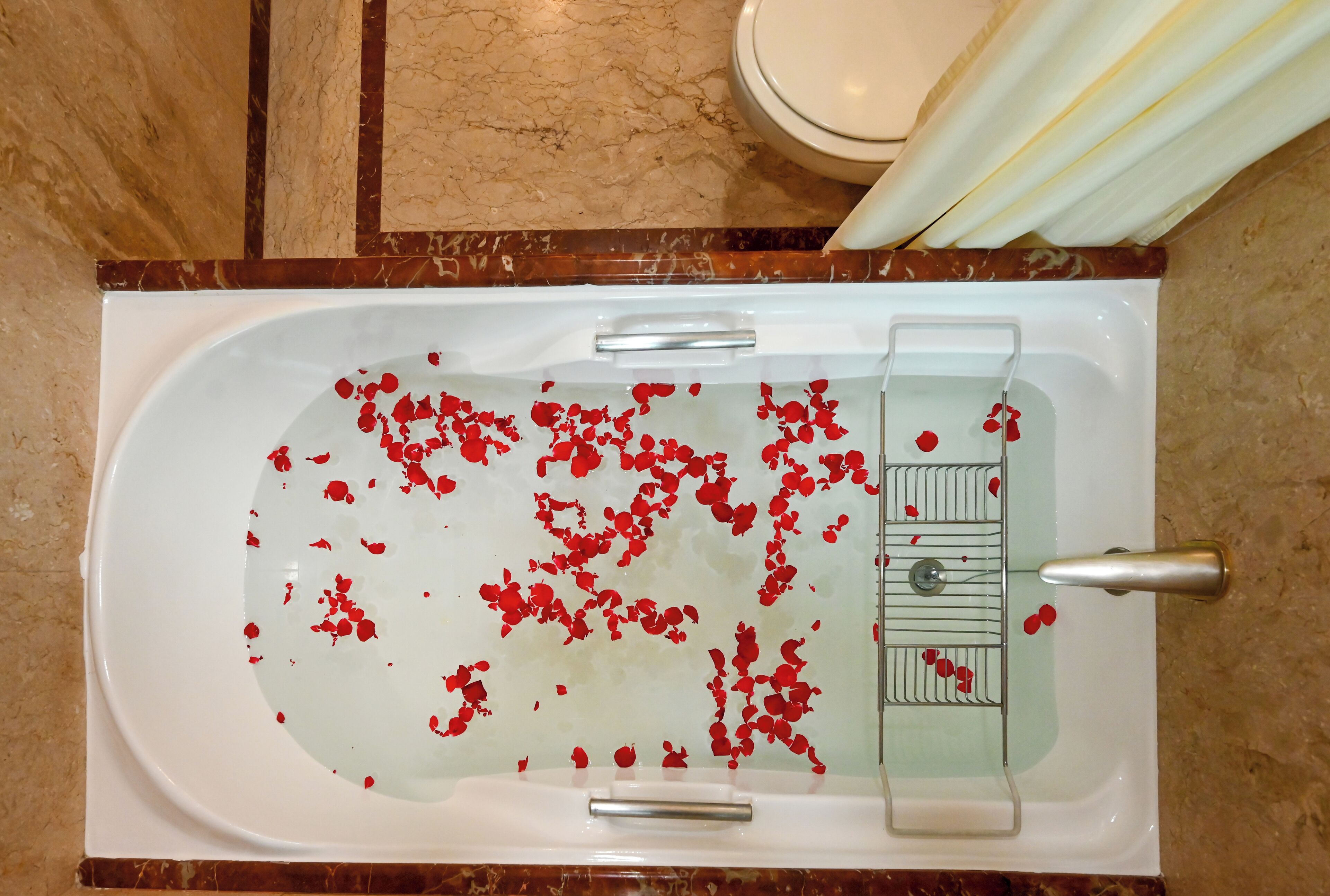 A bathroom with a bathtub filled with water and rose petals.