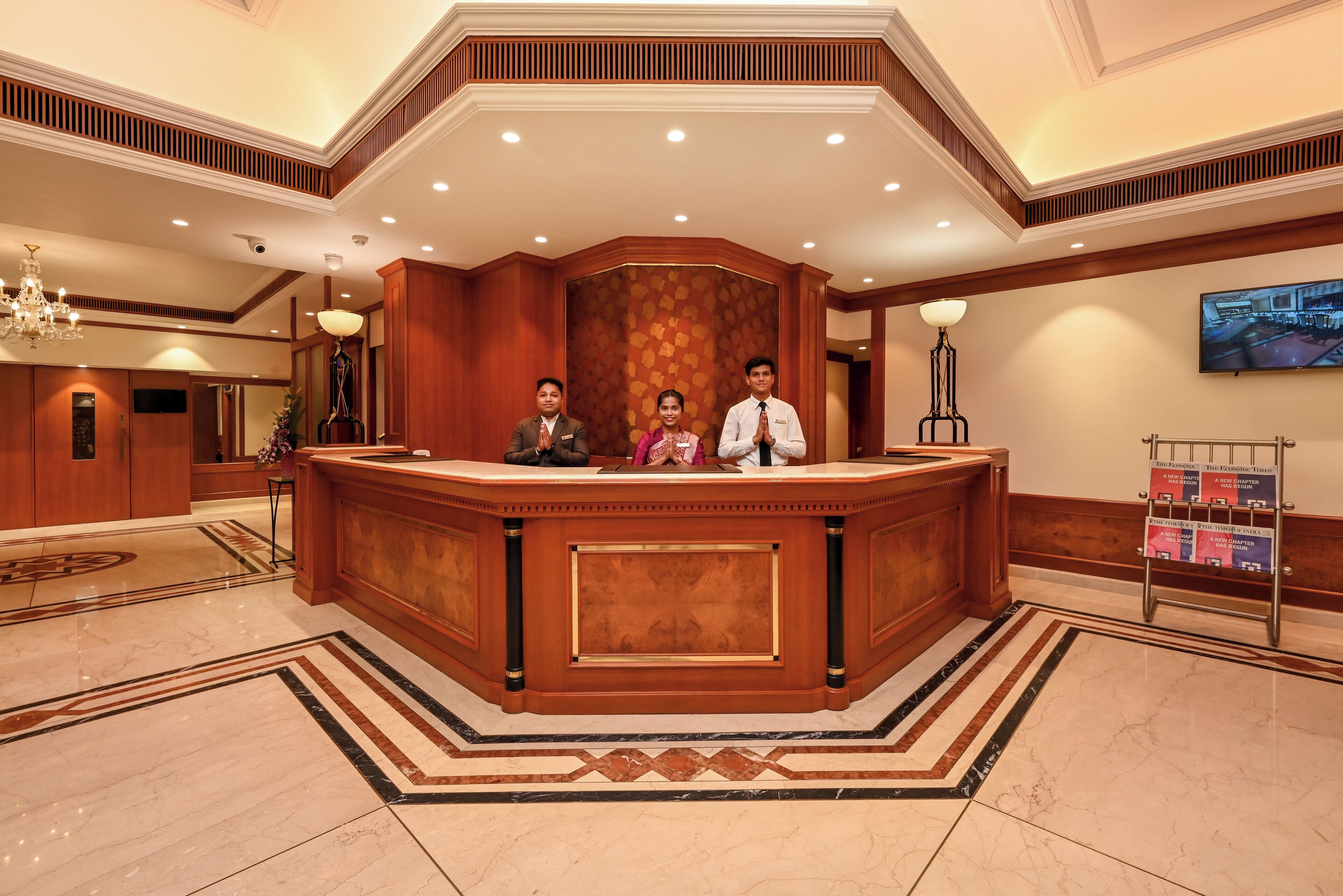 A reception area with a marble floor, wooden reception desk, and a chandelier.