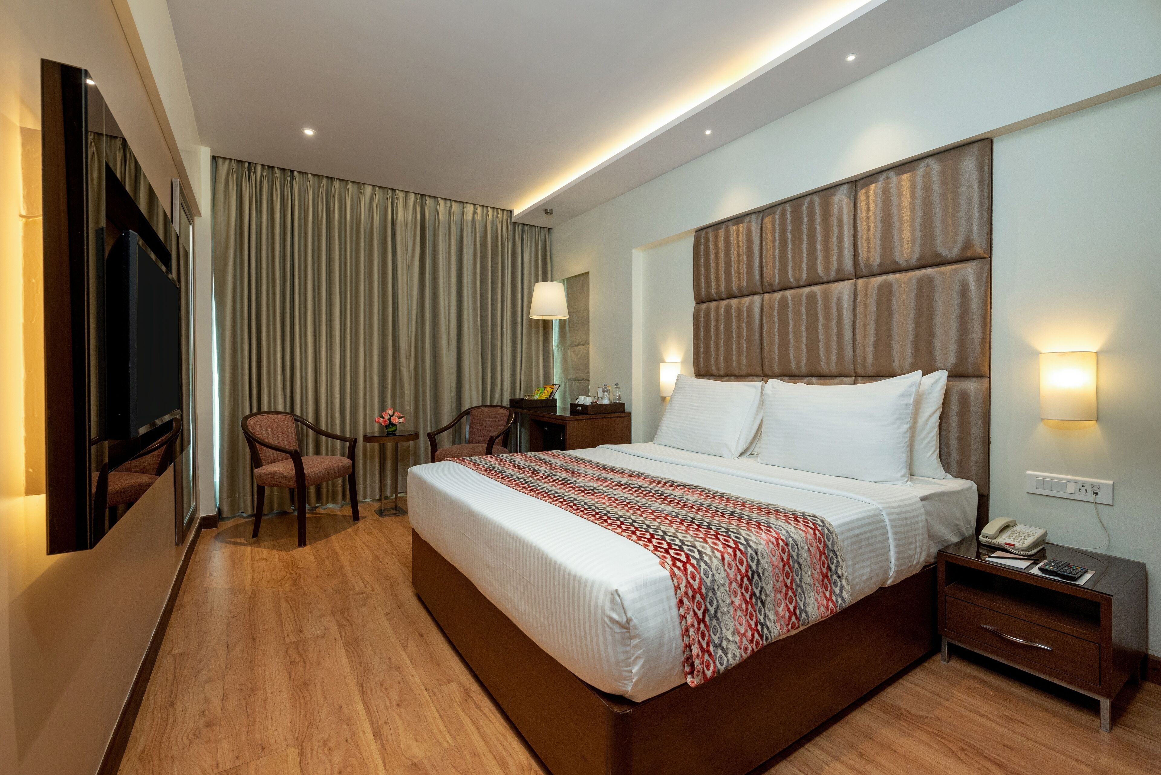 Une chambre d’hôtel avec un grand lit, un bureau avec une lampe, une chaise et un téléviseur.
