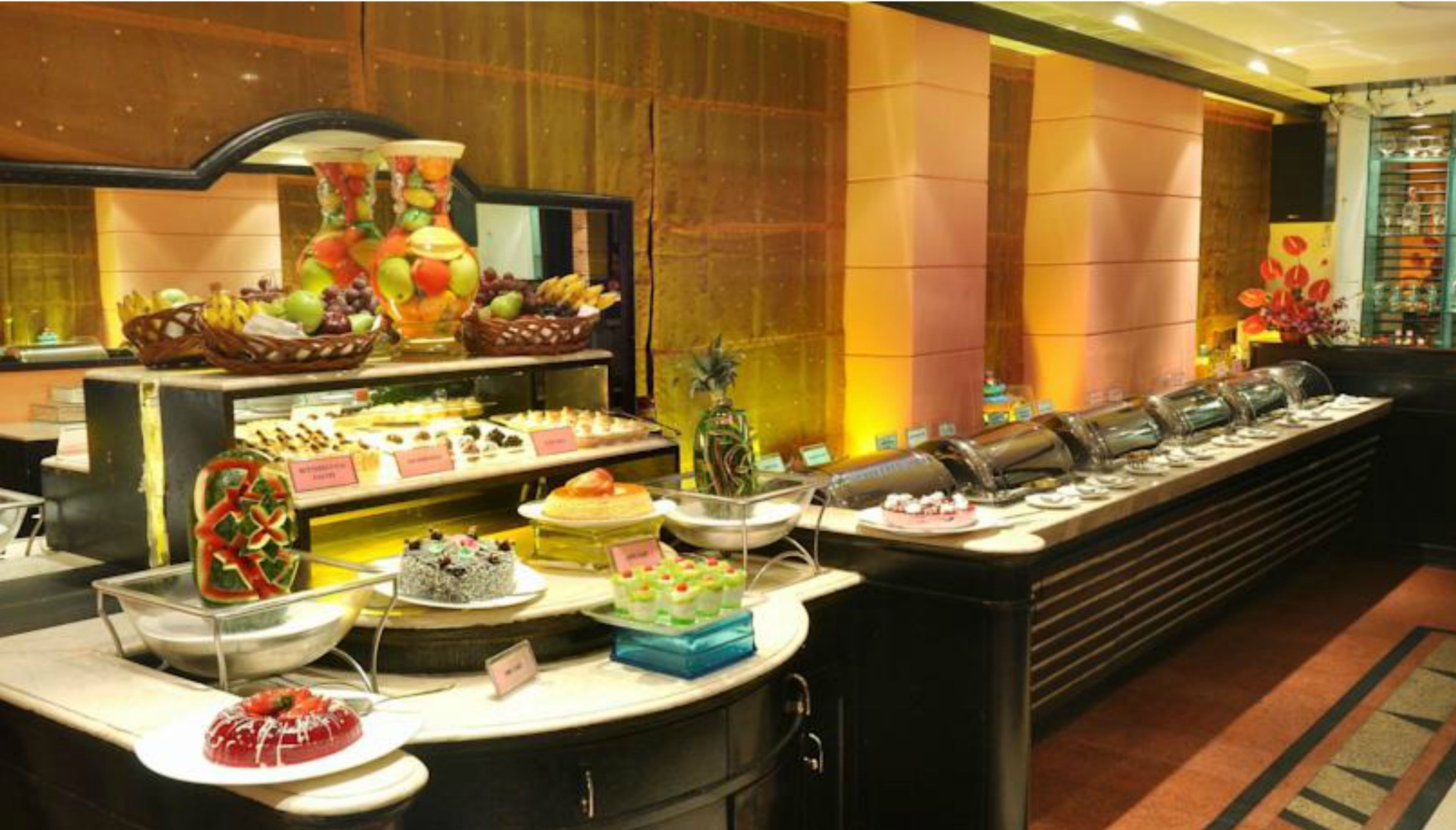 A buffet with various food items and a fruit display.