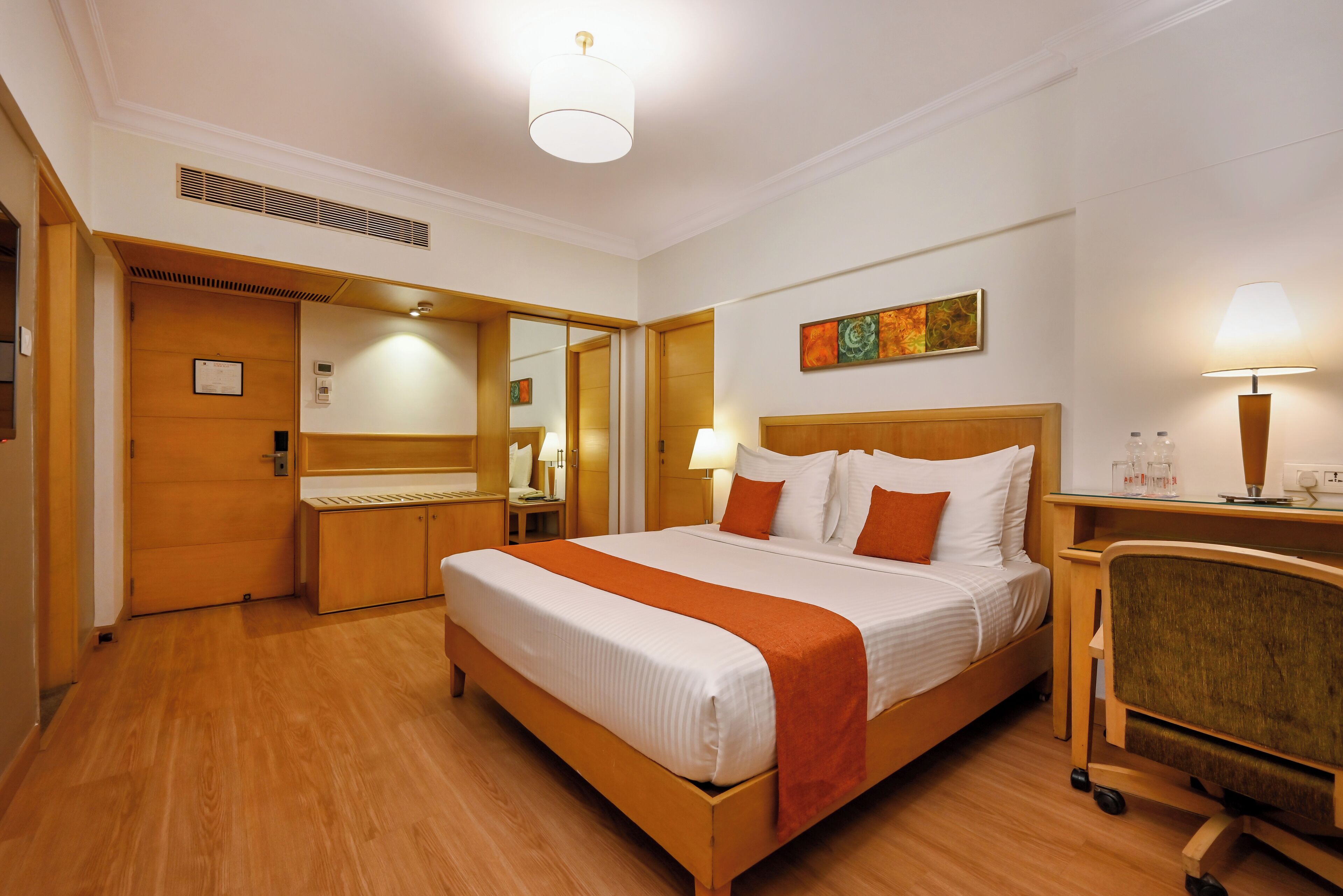 Ein Hotelzimmer mit einem großen Bett, einem Schreibtisch, einem Stuhl und einem Spiegel.