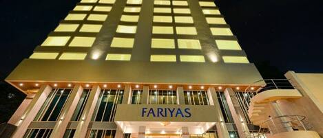 A modern hotel with a prominent "FARIYAS" sign, a central staircase, and a glass facade.