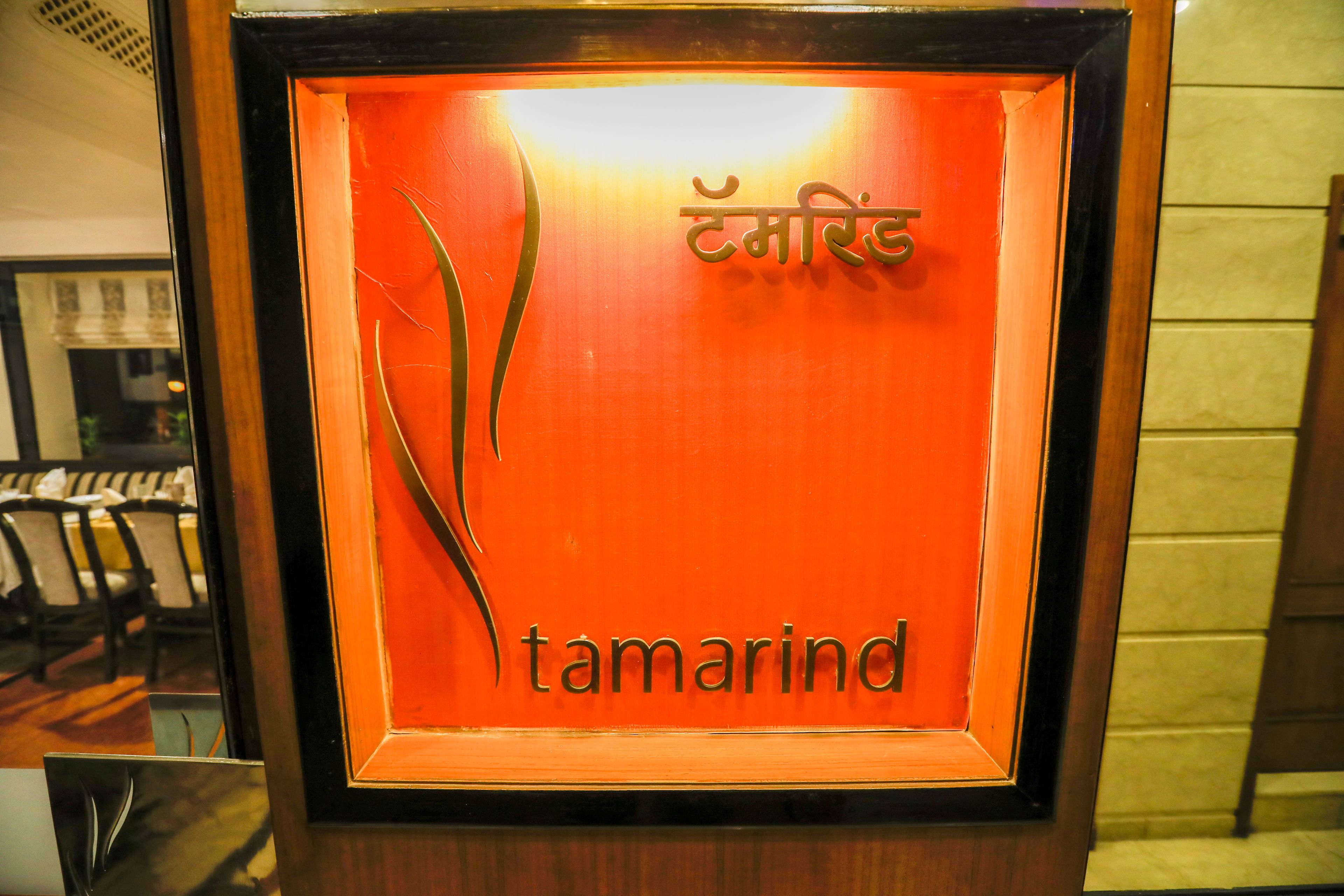 Ein gerahmtes Schild mit dem Schriftzug "tamarind" und einem dekorativen Element.