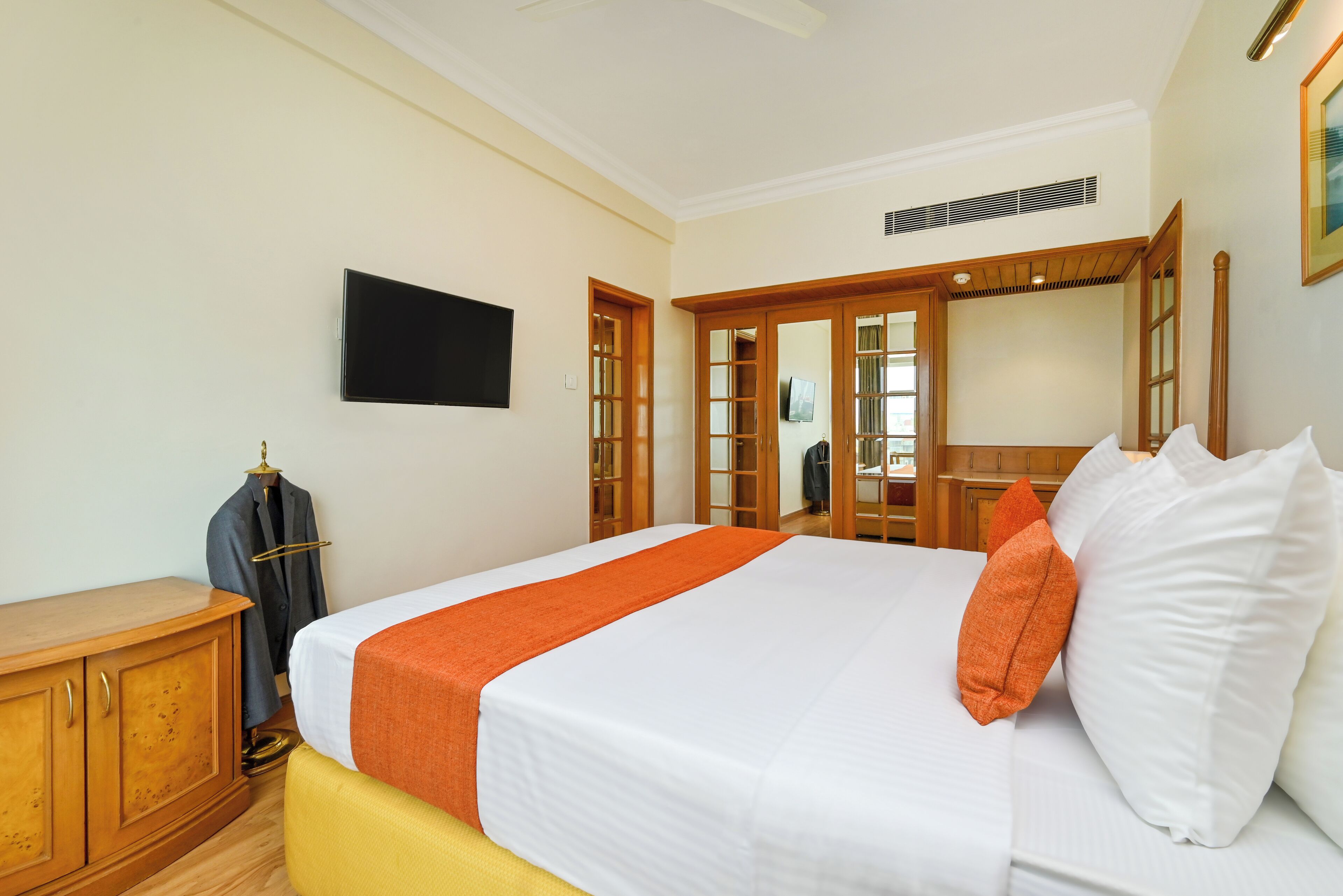 Una habitación de hotel con una cama, un armario de madera, un televisor y un espejo.