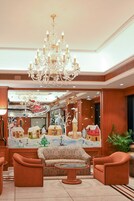 A lobby with a chandelier, patterned sofas, and a Christmas-themed mural.
