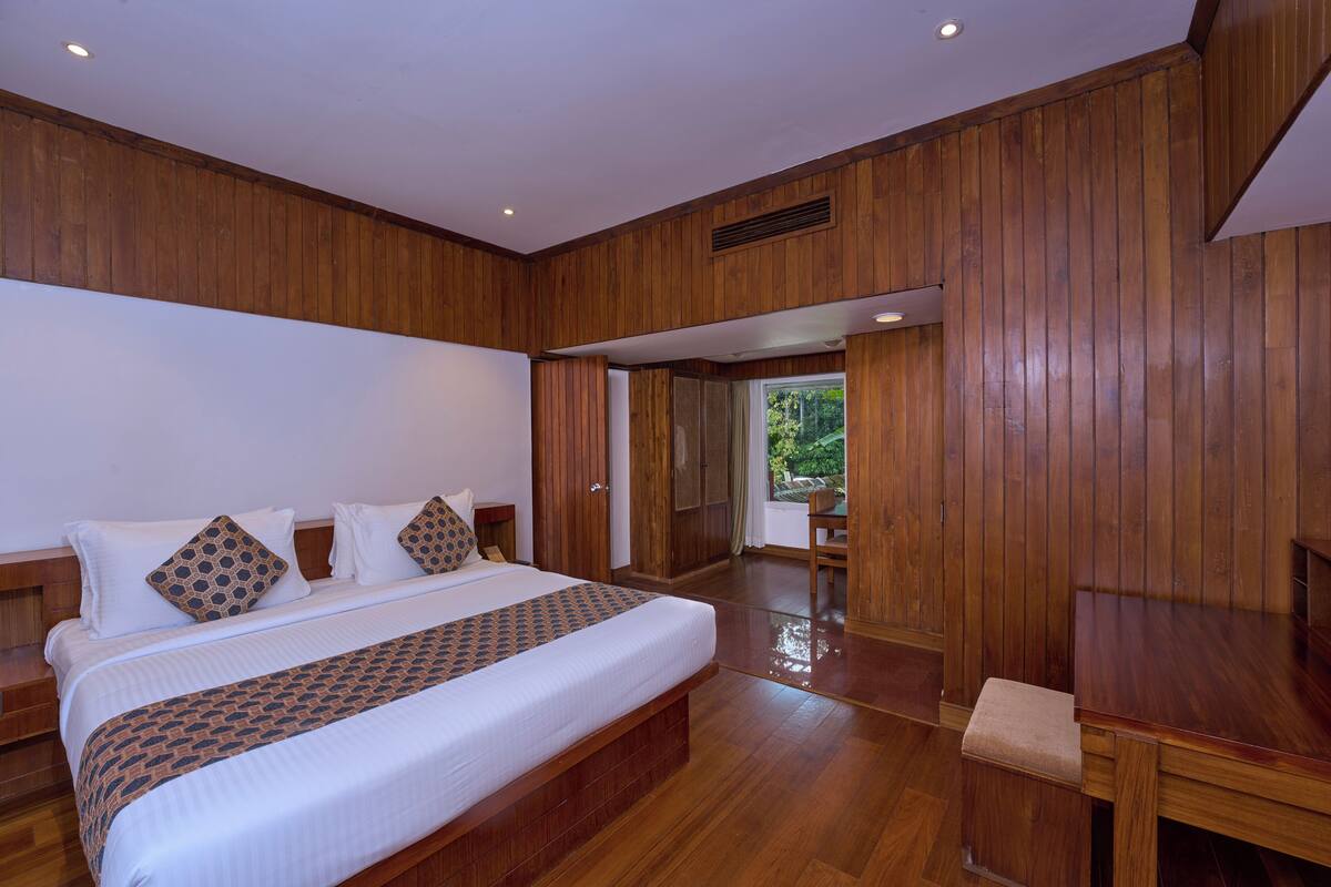 Un dormitorio espacioso con una cama grande, paneles de madera y vistas al exterior.