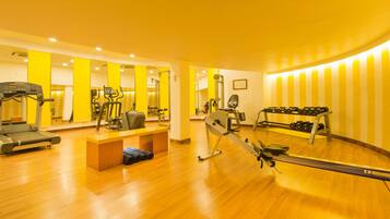 Un gimnasio con máquinas de cardio, pesas y espejos.