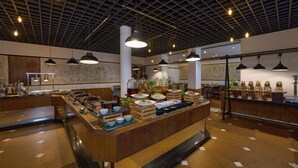 Un restaurante espacioso con una barra larga, múltiples lámparas colgantes y un techo alto con diseño de cuadrícula.