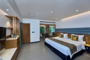 Quarto de hotel moderno com uma cama grande, uma escrivaninha, uma televisão e vista para o mar.