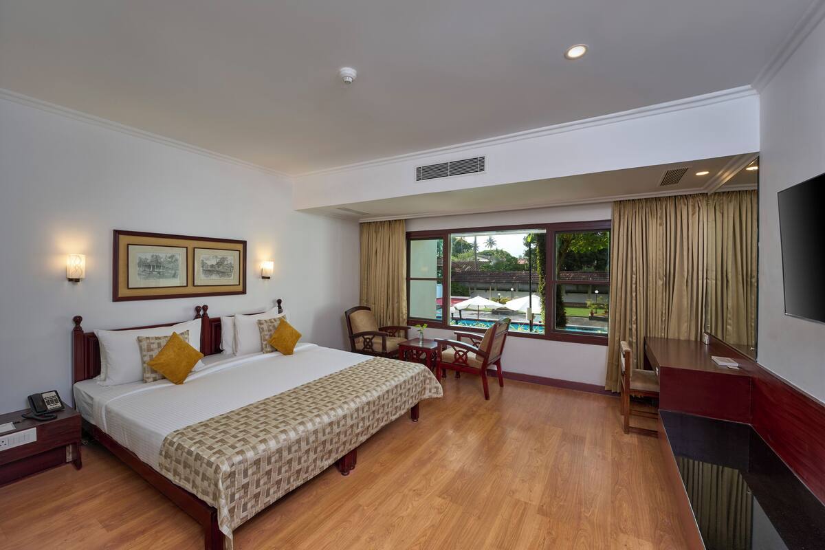 Una habitación de hotel con una cama grande, un escritorio, una silla y un televisor.