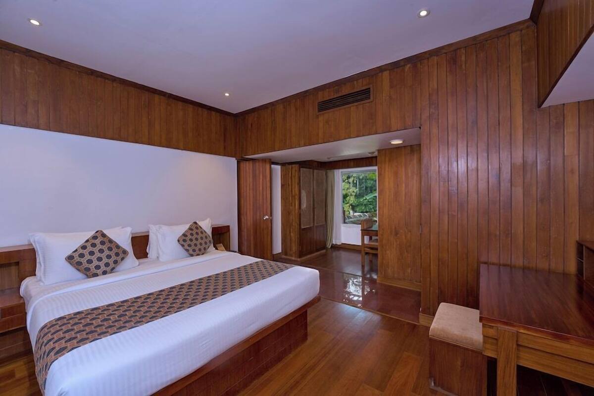 Un dormitorio con una cama grande, paneles de madera, una mesita pequeña y vistas al exterior.