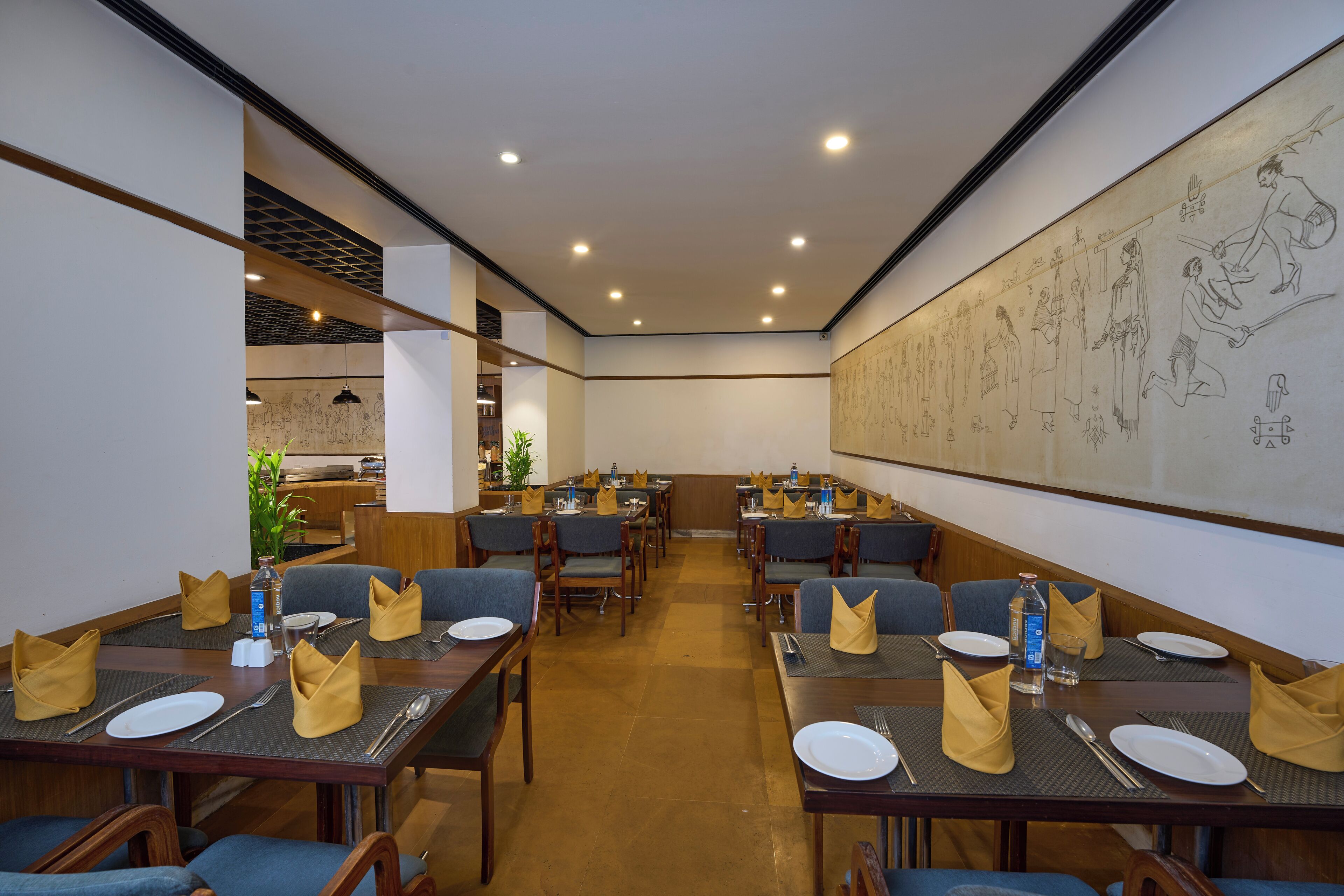 A restaurant with multiple tables set for dining, featuring a large mural on the wall and a modern ceiling design.