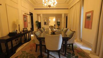 A formal dining room with a chandelier, a floral carpet, and a dining table set for six.