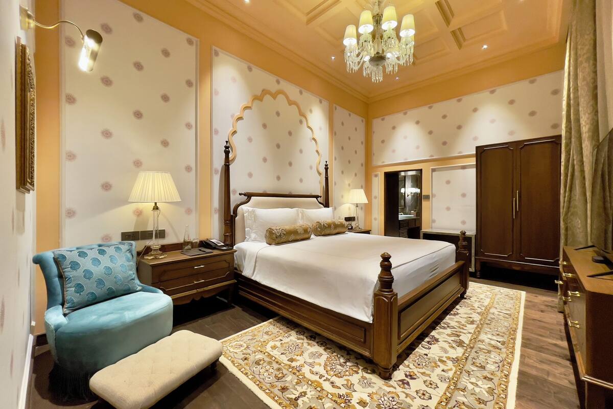 Une chambre à coucher avec un grand lit, une table de chevet, une chaise, une armoire et un lustre.