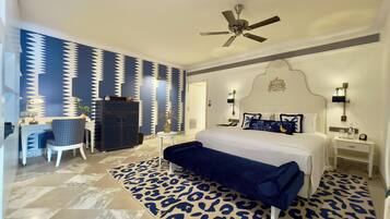 A bedroom with a bed, a desk, a chair, a wardrobe, and a ceiling fan.