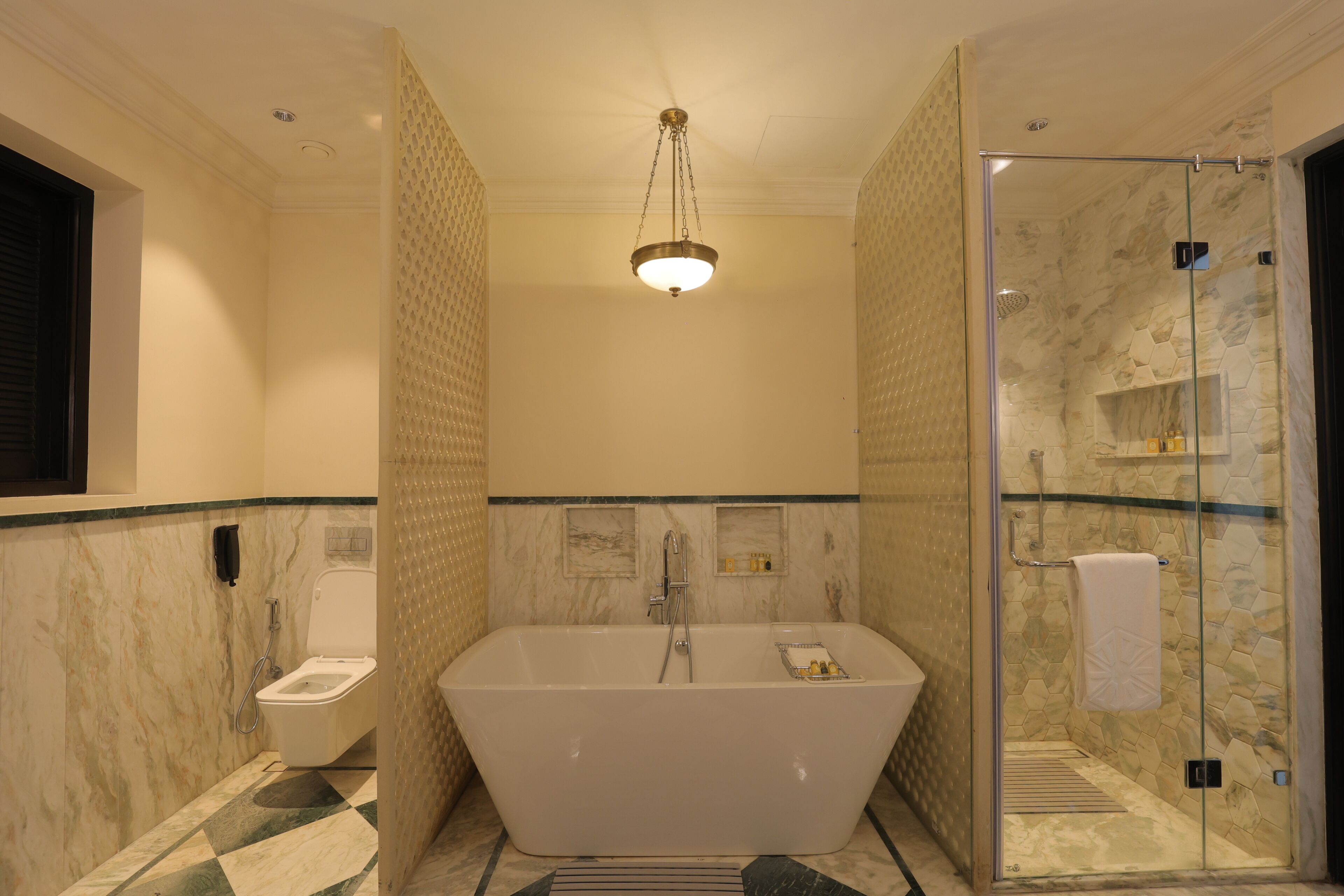 A modern bathroom with a freestanding bathtub, a glass-enclosed shower, and a marble-tiled floor.