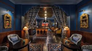 Un vestíbul d'hotel amb decoració ornamentada, una zona de bar i zones d'estar.